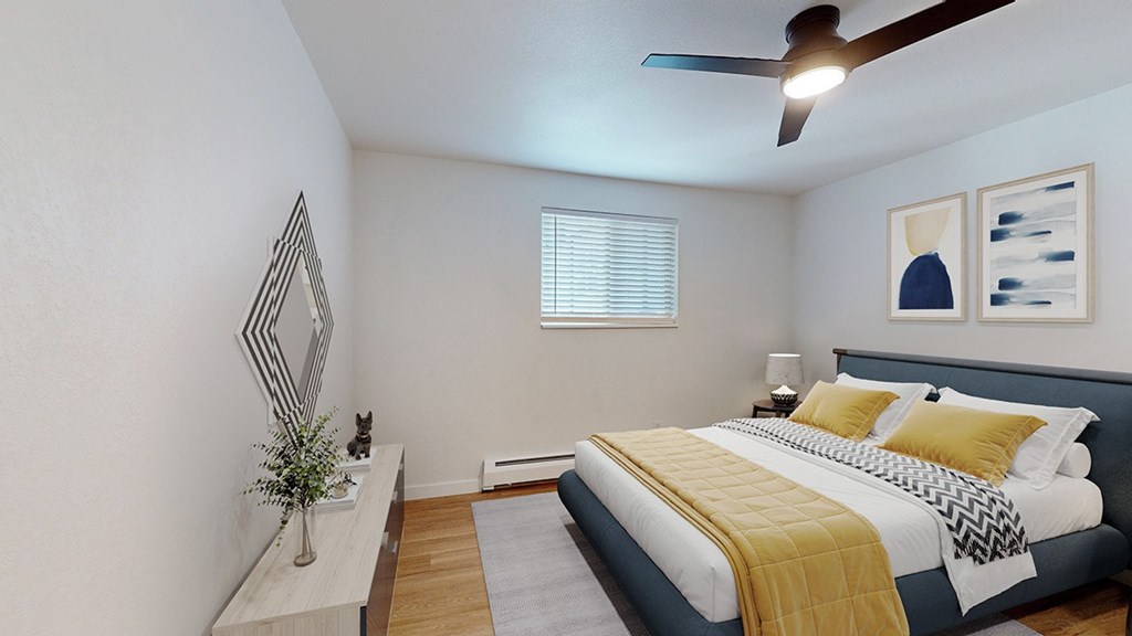 A bedroom with a bed, a plant, and a mirror.