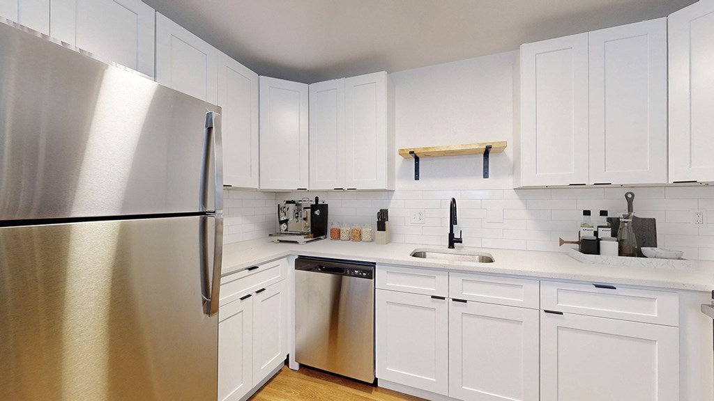 A kitchen with white cabinets and a stainless steel refrigerator.