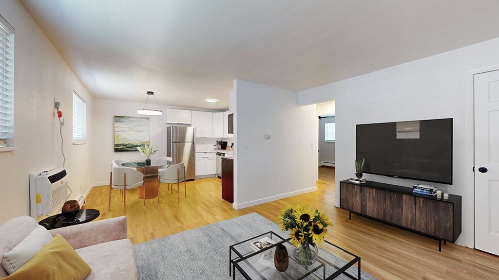 A modern living room with a grey sofa, a glass coffee table, and a television.