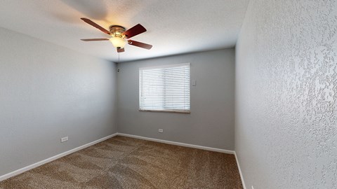A room with a ceiling fan and a window with blinds.