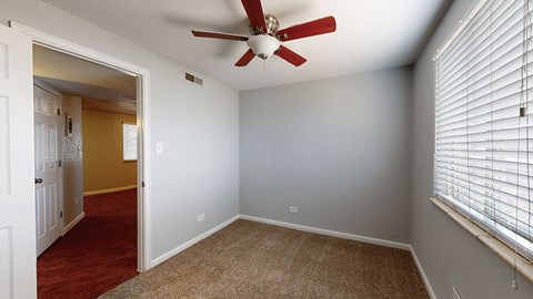 A room with a ceiling fan and a window with blinds.