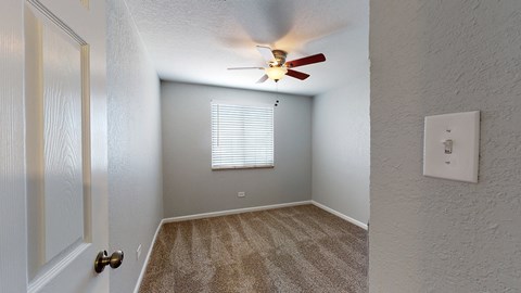 A room with a ceiling fan and a window with blinds.