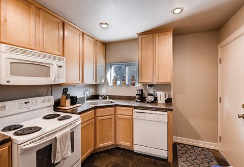 A kitchen with wooden cabinets and a white stove top oven.