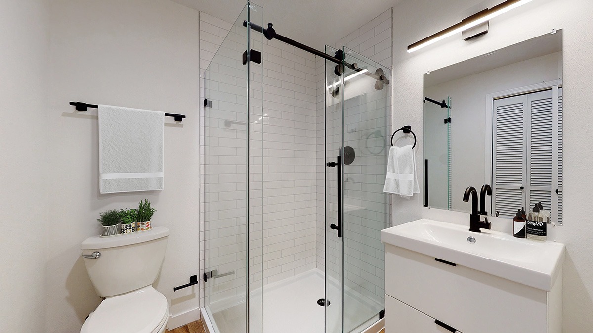 A white bathroom with a toilet, sink, and shower.