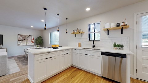 A kitchen with white cabinets and a wooden floor.