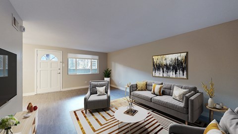 A living room with a grey couch, a coffee table, and a painting on the wall.