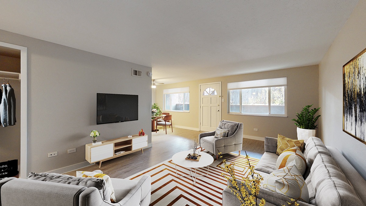 A living room with a grey couch, a white coffee table, and a television on the wall.