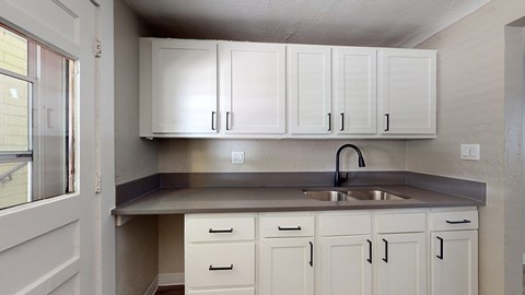 A kitchen with white cabinets and a stainless steel sink.