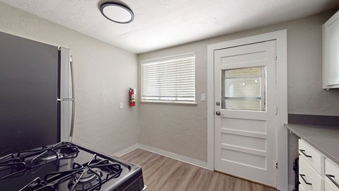 A kitchen with a black stove top oven and a white door.