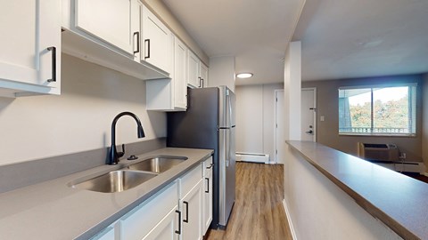 A kitchen with white cabinets and a stainless steel refrigerator.