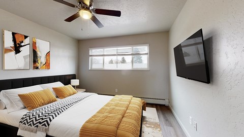 A bedroom with a bed, a ceiling fan, a window, and a painting on the wall.