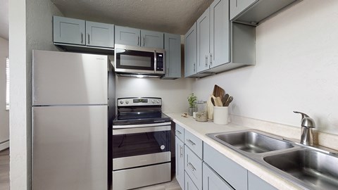 A kitchen with a stainless steel refrigerator, microwave, and oven.