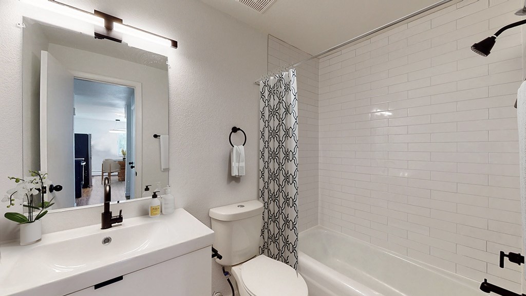 A white bathroom with a toilet, sink, and shower.