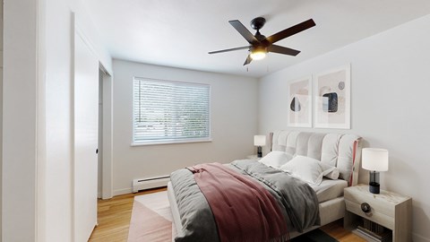 A bedroom with a bed, nightstand, and a ceiling fan.