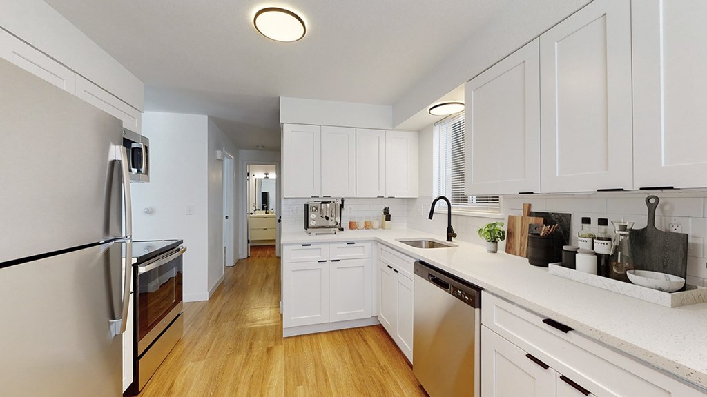 A modern kitchen with white cabinets and stainless steel appliances.