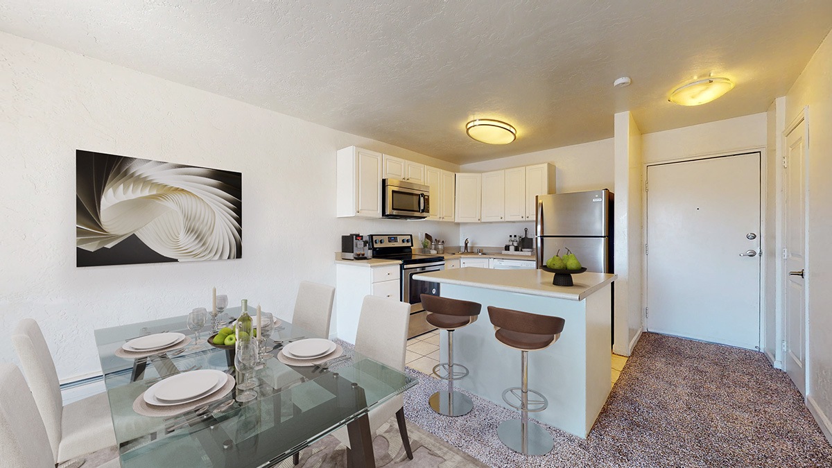A modern kitchen with a glass dining table set for two.