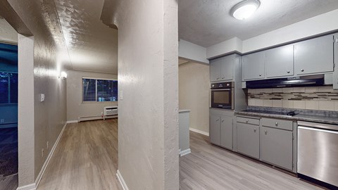 A kitchen with stainless steel appliances and wooden floors.