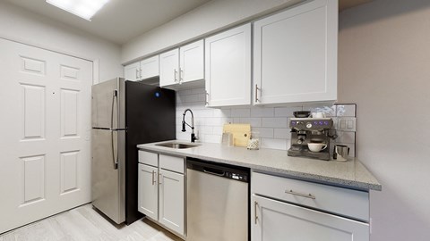 A kitchen with white cabinets and a black refrigerator.