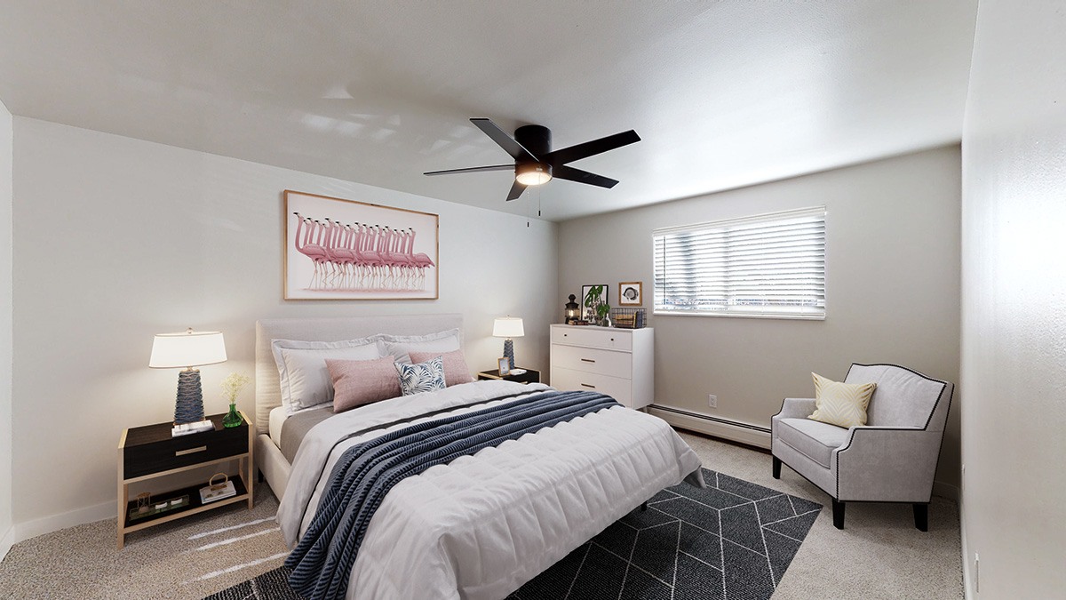 A bedroom with a bed, a chair, and a ceiling fan.