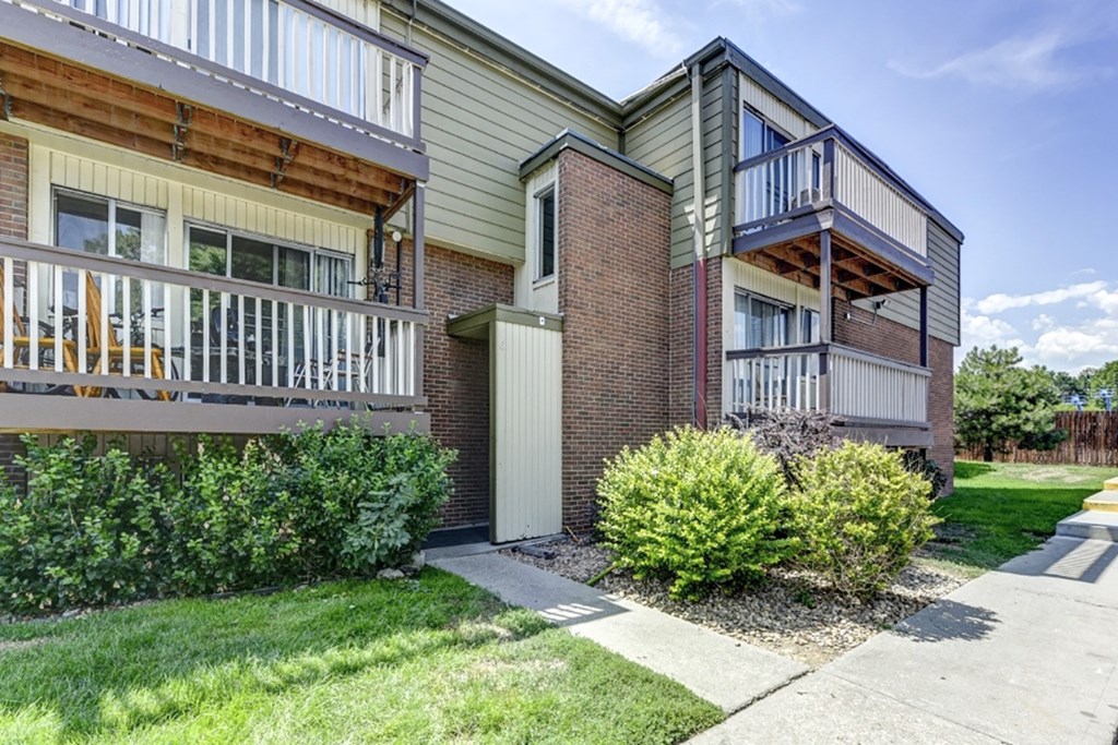 A building with a balcony and a small garden in front.