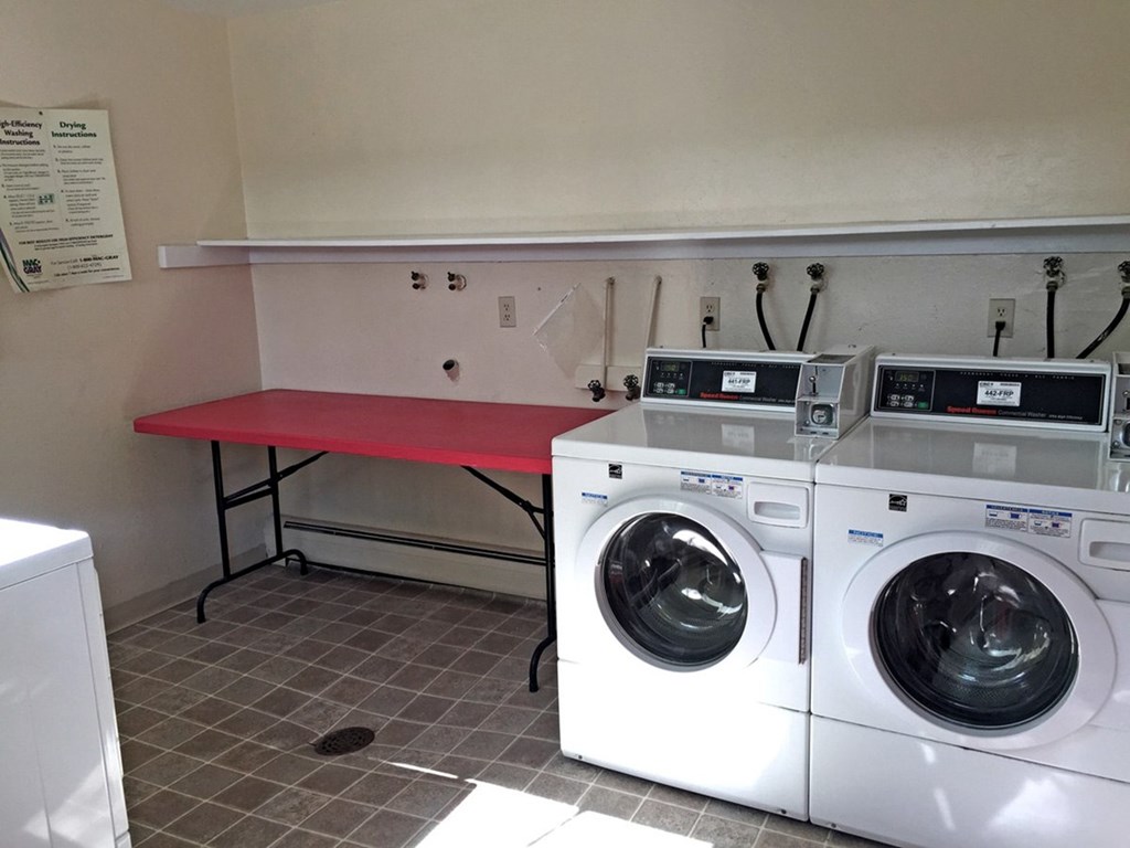 A laundry room with a washer and dryer and a red table.