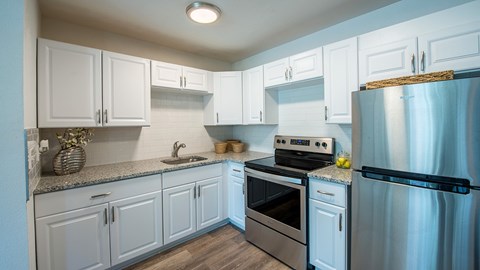 A kitchen with white cabinets and a stainless steel refrigerator.