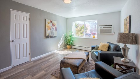 A living room with a white door, a brown couch, and a painting on the wall.
