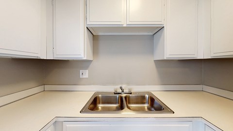A kitchen with a double sink and white cabinets.