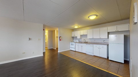 A kitchen area with white cabinets and a yellow line on the floor.