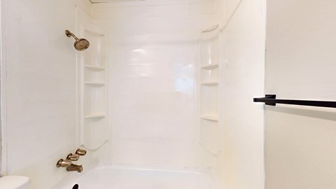A white bathroom with a tub, toilet and shelves.