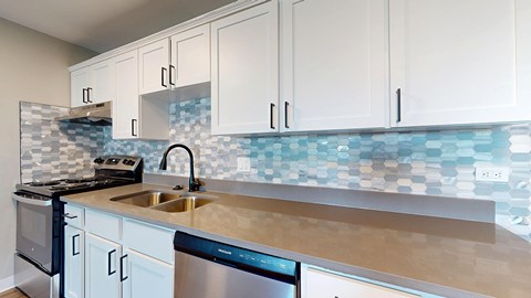 A kitchen with white cabinets and a blue tile backsplash.