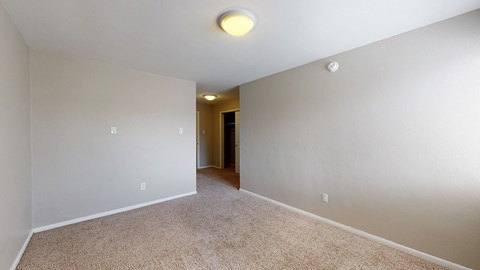 A room with a carpeted floor and a doorway leading to another room.