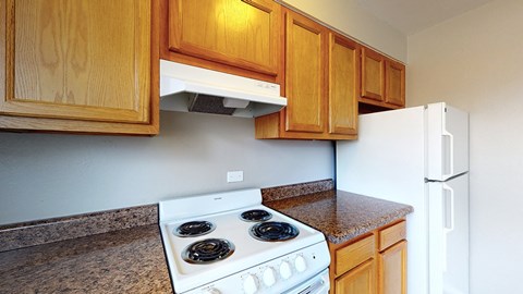 A kitchen with a white stove and wooden cabinets.