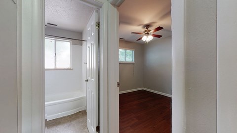 A room with a ceiling fan and a bathtub.