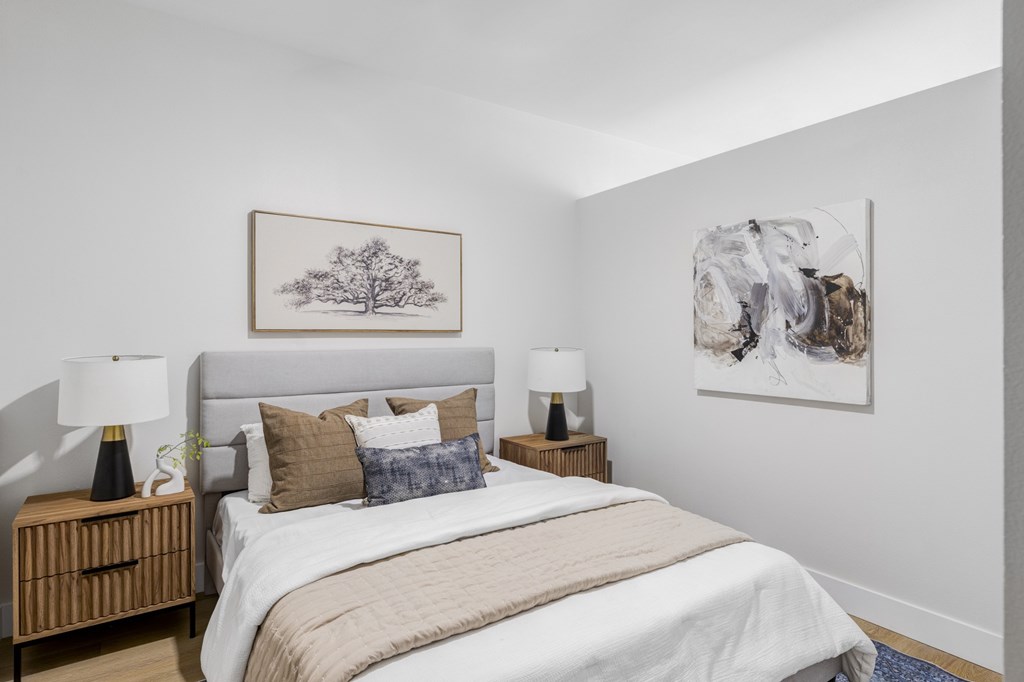 A bedroom with a large bed and two pieces of artwork on the wall.