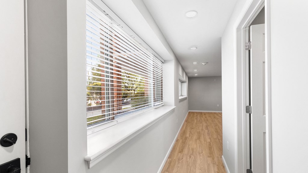 a long hallway with a large window with blinds on it