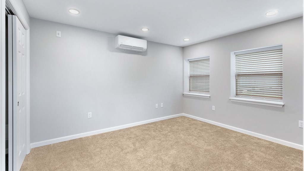 an empty room with carpet and two windows