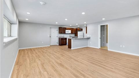 an empty living room and kitchen with a wood floor