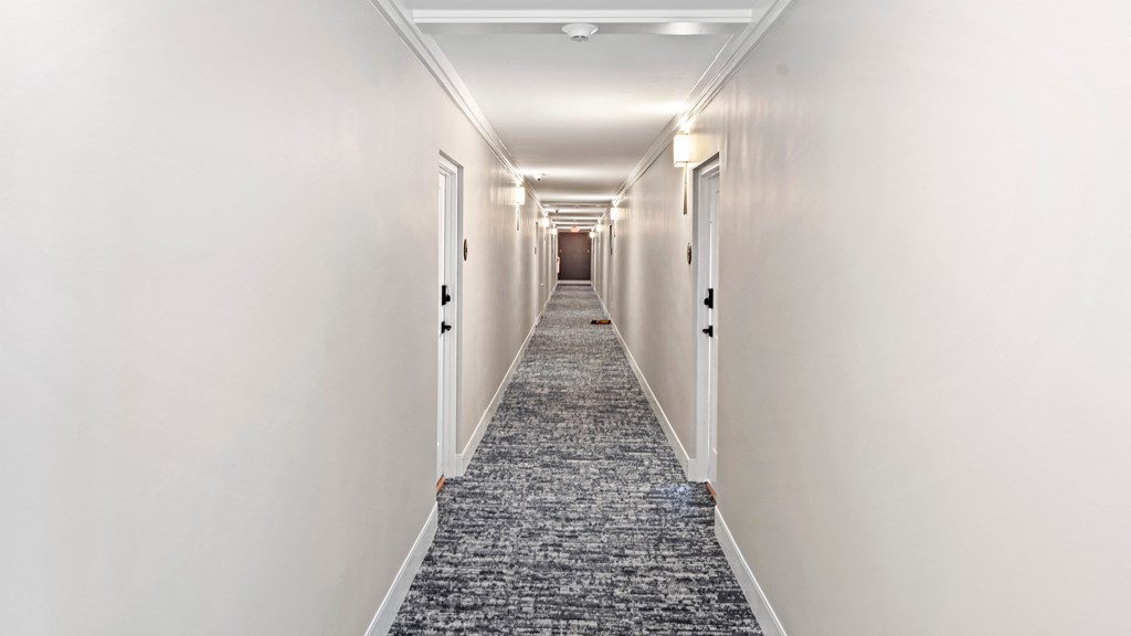 a carpeted hallway with white walls and white doors