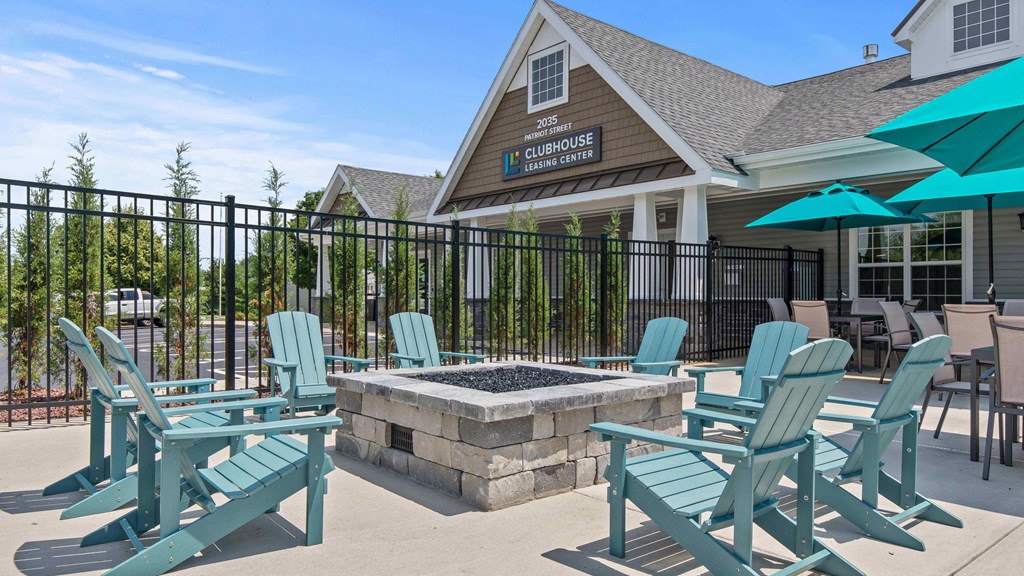 a patio with blue chairs and umbrellas and a fire pit
