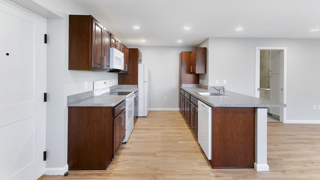 a kitchen with wooden cabinets and white appliances and a wood floor