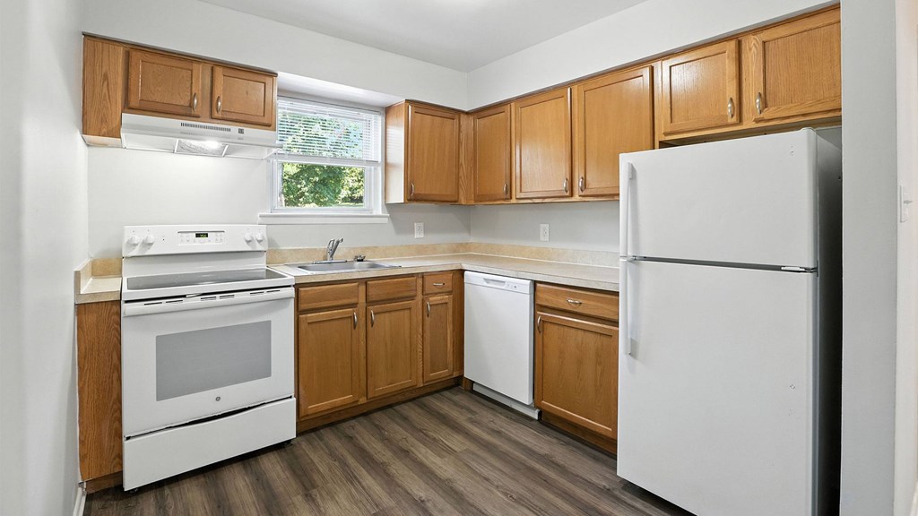 A kitchen with white appliances and wooden cabinets.