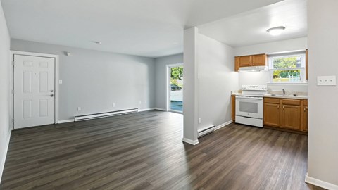 A spacious living room with a kitchen area in the background.