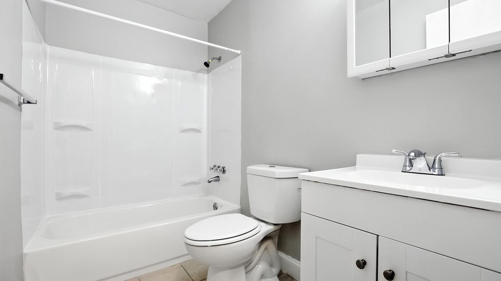 A white bathroom with a toilet, sink, and bathtub.