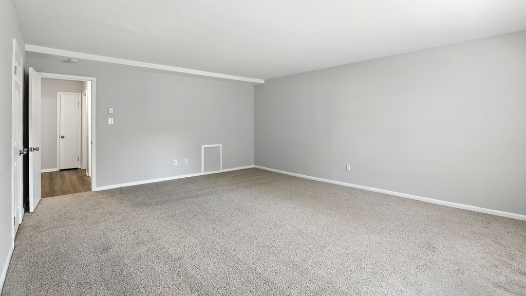 A sparsely furnished room with a carpeted floor and white walls.