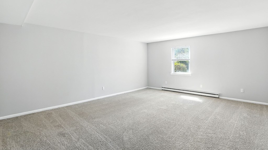 A room with a carpeted floor and a window.