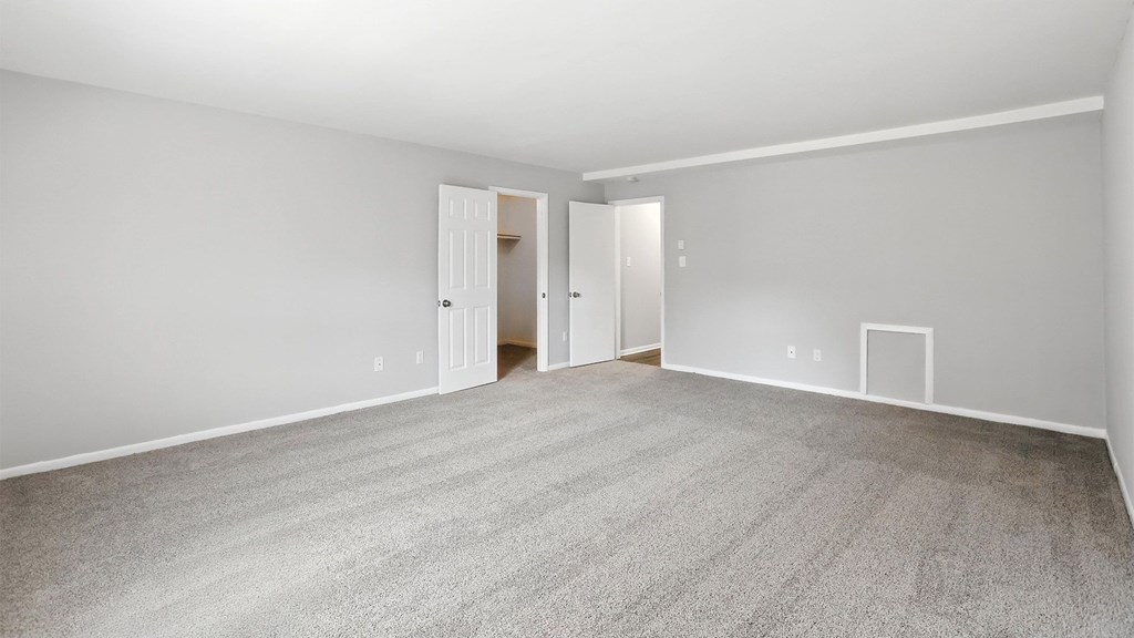 A room with a carpeted floor and two doors.