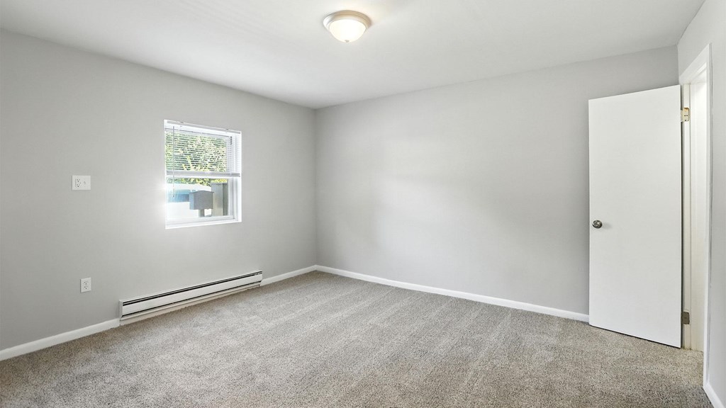 A room with a window, carpet, and a door.