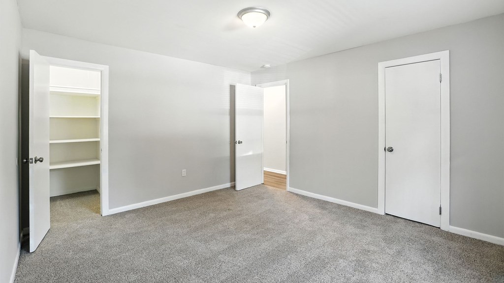 A spacious room with white doors and a carpeted floor.