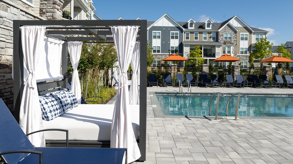 a pool with a chaise lounge chair in front of a poolside house